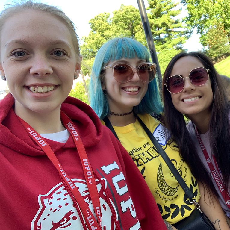 A selfie of three smiling students outside
